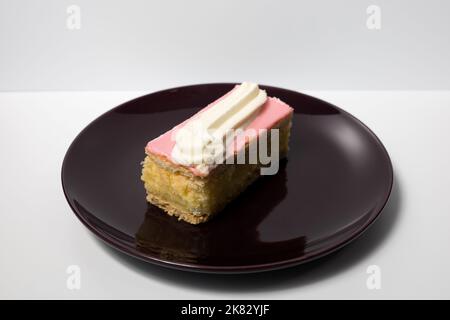 Traditionelles holländisches rosafarbenes Tompouce-Gebäck, gefüllt mit Creme auf weißem Hintergrund. Stockfoto