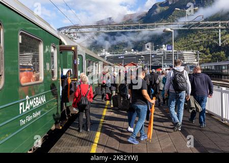 Nach einer schönen Zugfahrt durch die Natur mit der Flam-Bahn steigen die Menschen aus dem Zug aus, um zum im Hafen von Flam verankerten Kreuzschiff zurückzukehren Stockfoto