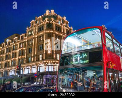 VERKAUF BUS TRANSPORT LONDON SHOPPING Harrods Kaufhaus in der Winternacht Abenddämmerung mit Sale Lights Shopper vorbei an Taxis und roten Bus im Vordergrund auf der Route 14 Knightsbridge London SW1 Stockfoto