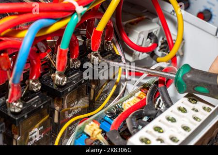 Reparatur des Spannungsstabilisators. Ein Elektriker entschrauben die Stromkabel des Centurion Stabilisators - Russland, Anapa, 10.20.2022 Stockfoto