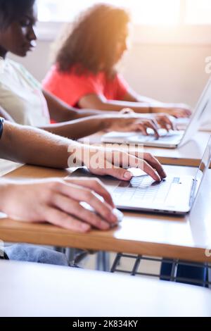 Vertikale Nahaufnahme des Laptops im Klassenzimmer. Eine multiethnische Gruppe von Gymnasiasten studiert mit Computern. Digitalisierte Bildung und Stockfoto
