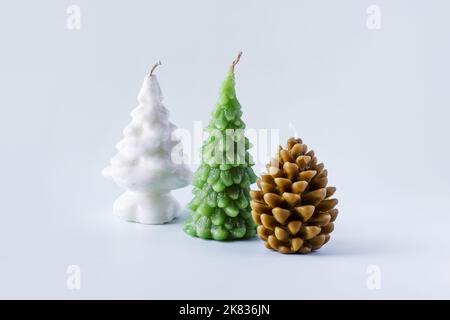 Braune Weihnachtskerze in Form einer Kiefer, grüne und weiße Kerzen in Form eines Weihnachtsbaums auf blauem Hintergrund Stockfoto