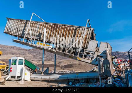 Ein Sattelkipper und die schwere Ausrüstung, die zum Verteilen und Zerkleinern von festen Abfällen in den Boden mit Bulldozern und Bodenverdichtern verwendet wird. Stockfoto