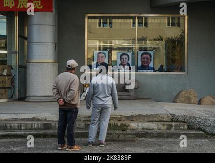 15. Oktober 2018, Tumen, China: Ein Paar, das die Fenster vor einem chinesischen Geschäft betrachtet, das Porträts der verstorbenen nordkoreanischen Führer Kim Il-sung (links) und Kim Jung-il (rechts) sowie der Großmutter von Kim Jung-un, Kim Jong-suk, verkauft. Die chinesisch-nordkoreanische Grenze, Grenzübergang Namyang-Tumen, von Tumen aus gesehen, in der Autonomen Präfektur Yanbian. (Bild: © Jasmine Leung/SOPA Images via ZUMA Press Wire) Stockfoto