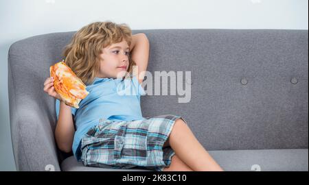 Glückliches Kind, das frische Pizza in großen Scheiben beißt. Kleiner Junge, der Pizza isst. Niedlicher kleiner Junge isst Pizza. Glücklich hübsch jung teen junge halten Scheibe Stockfoto