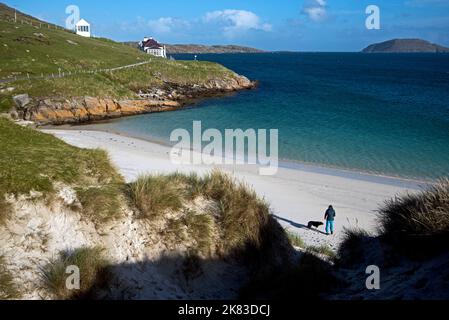 Junge Frau mit Hund auf Traigh a Bhaigh (East Beach), in der Nähe des Startens des Hebriden Way auf Vatersay in den Äußeren Hebriden, Schottland, Großbritannien. Stockfoto