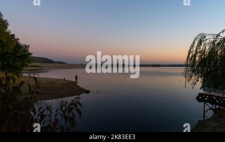 Budeasa Mare, Rumänien - 18. Oktober 2022: Fischer am Ufer des Budeasa-Sees in Zentralrumänien bei Sonnenuntergang Stockfoto