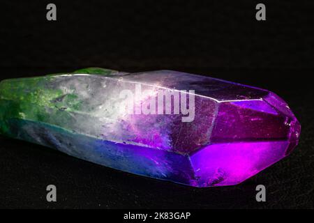 Lebhaftes farbenprächtiges, auf einer schwarzen Oberfläche isoliertes Cocktail-Aura-Makro mit Quarzpunkt. Farbenfroh, rosa, blau, weiß, lila und grün, von Menschen verstärkt Stockfoto