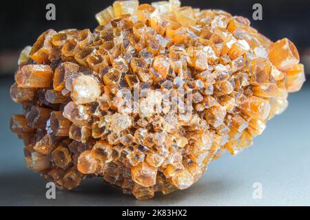 Aragonit-Cluster, orangefarbener Kristall auf der silbernen Oberfläche. Makro-Foto aus orangefarbenem Kristall. Kristallcluster-Block. Corona-förmiger Kristall Stockfoto