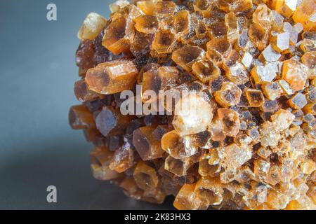Aragonit-Cluster, orangefarbener Kristall auf der silbernen Oberfläche. Makro-Foto aus orangefarbenem Kristall. Kristallcluster-Block. Corona-förmiger Kristall Stockfoto