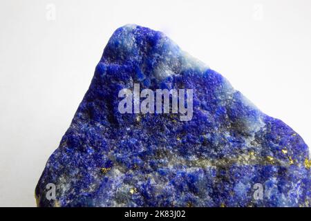 Roher Lapislazuli-Felsen auf weißem Hintergrund. Unpoliertes Stück Lapislazuli auf weißem Hintergrund. Lapislazuli mit Pyritflecken. Stockfoto