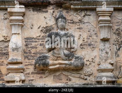 Alte Stuckschnitzerei in Lebensgröße der sitzenden Gottheit an der Wand des buddhistischen Tempels Wat Chet Yot oder Wat Jed Yod, historisches Wahrzeichen von Chiang Mai, Thailand Stockfoto