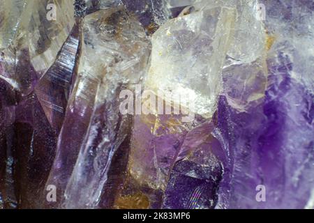 Ultra-Makro-Nahaufnahme eines natürlichen violetten Amethyst-Quarzanhäufens, isoliert auf schwarzem Hintergrund Stockfoto