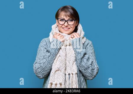 Winterporträt der reifen Frau in warmen Kleidern auf blauem Hintergrund Stockfoto