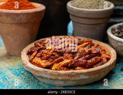 Bunte gemahlene würzige Chilischoten, Pimento und Curcuma ist Tontöpfe aus nächster Nähe auf einem Holztisch Stockfoto