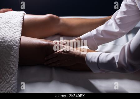 Goiânia, Goias, Brasilien – 18. Juli 2022: Masseur, der auf einer Bahre liegend eine Kniemassage gibt. Stockfoto