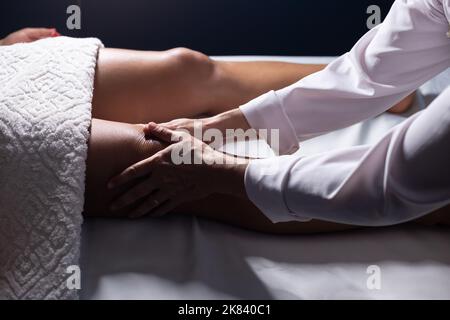 Goiânia, Goias, Brasilien – 18. Juli 2022: Masseur, der auf einer Bahre liegend eine Kniemassage gibt. Stockfoto