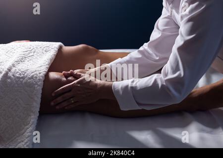 Goiânia, Goias, Brasilien – 18. Juli 2022: Masseur, der auf einer Bahre liegend eine Kniemassage gibt. Stockfoto