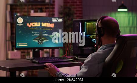 Kaukasischen Gamer spielen rasante Weltraum-Shooter-Simulation genießen Sieg nach dem Sieg schwierigen Gaming-Wettbewerb auf dem pc. Mann feiert das siegreiche Gefühl im Internet-Multiplayer-Action-Spiel. Stockfoto