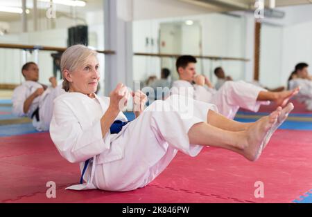 Sportler Mann und Frau im Kimono machen Bauchübungen im Fitnessstudio Stockfoto