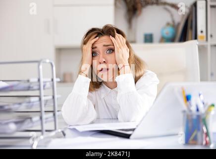 Erschöpfte Büroangestellte, die an ihrem Schreibtisch sitzt Stockfoto