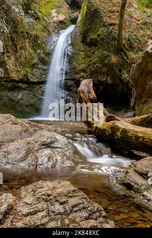 Schöner, glatter weißer Wasserfall, der zwischen moosbedeckten Felsen fällt Stockfoto