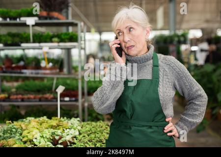 Verärgerte ältere Frau in einem Fabrikgeschäft, die am Telefon sprach Stockfoto