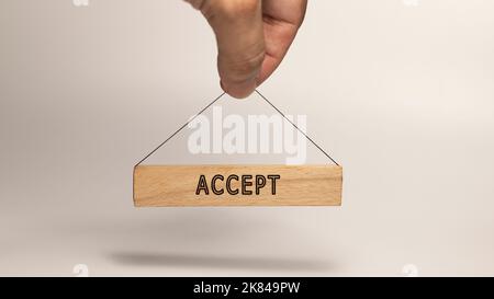 Akzeptieren auf Holzrahmen geschrieben. Handhängendes Rahmenkonzept. Hintergrund ist weiß Stockfoto