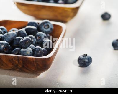 Auf weißem Grund zwei Schalen mit frischen Blaubeeren. Nahaufnahme. Viele Vitamine, Antioxidantien, leichte Sommerdessert, Süßwaren-Zutat. Coo Stockfoto