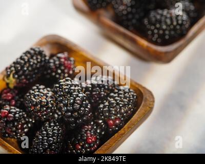 Nahaufnahme. Frische Brombeeren, Maulbeeren in Schalen. Isoliert auf weißem Hintergrund. Vitamine, Antioxidantien. Leichtes Sommerdessert, vegetarische Bio-Lebensmittel Stockfoto