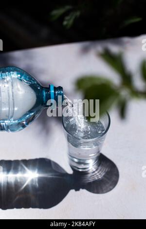 Wasser in einen Glasbecher gießen. Konzept der gesunden Getränke. Stockfoto