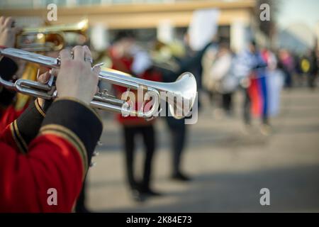 Orchester mit Blasinstrumenten. Trompeter in zeremoniellen Uniformen. Rote Militärkleidung. Musiker auf der Straße. Stockfoto
