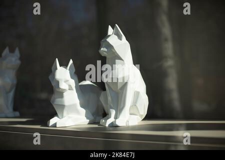 Kubische Figuren von Katzen. Skulptur der weißen Katze. Inneneinrichtung. Licht fällt auf ein Objekt aus Kunststoff. Stockfoto