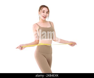 Junge asiatische Frau in Sportkleidung Messung Taille mit Band Stockfoto