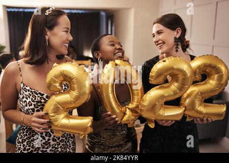 Waren bereit für das neue Jahr. Eine vielfältige Gruppe von Freunden, die zusammen standen und 2022 Ballons während einer Neujahrsfeier hielten. Stockfoto