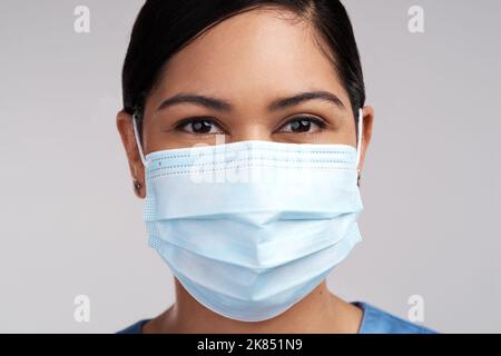 Äpfel machen mir keine Ahnung. Porträt eines jungen Arztes mit einer chirurgischen Gesichtsmaske vor weißem Hintergrund. Stockfoto