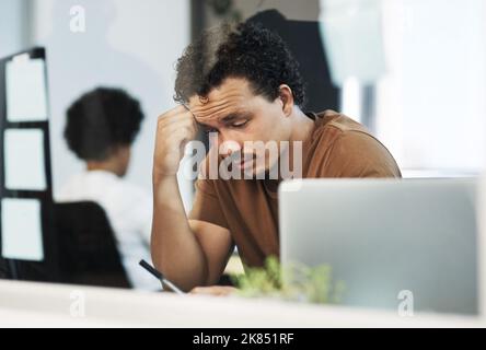 Das macht keinen Sinn. Ein hübscher junger Geschäftsmann sitzt im Büro und fühlt sich gestresst, während er sein Handy benutzt. Stockfoto