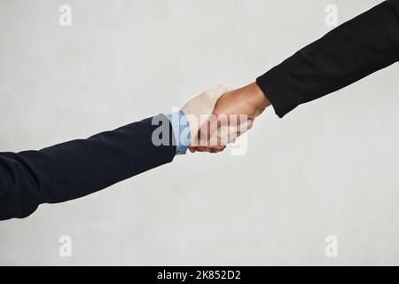 Ein Gewinn für mich ist ein Gewinn für Sie. In einem modernen Büro wurden zwei nicht erkennbare Geschäftsfrauen in einem hohen Winkel aufgenommen, die sich die Hände schüttelten. Stockfoto