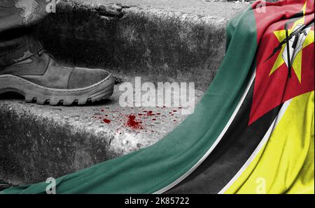 Das Bein des Militärs steht auf der Stufe neben der Flagge von Mosambik, dem Konzept des militärischen Konflikts Stockfoto