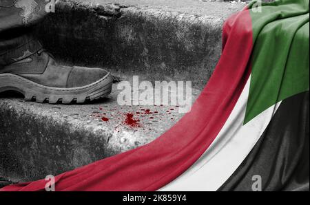 Das Bein des Militärs steht auf der Stufe neben der Flagge des Sudan, dem Konzept des militärischen Konflikts Stockfoto