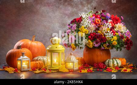 Happy Thanksgiving Konzept. Gemüse, Laterne, Kerzen und wunderschöne Herbstblumen in einer Kürbisvase. Stockfoto