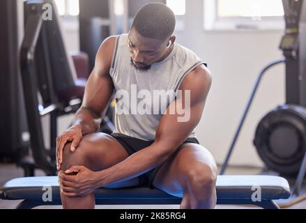 Schwarzer Mann, Fitness und Knieverletzung im Fitnessstudio nach dem Training, Training oder intensiven Übungen. Kopfhörer, Gesundheit und Bodybuilder männlich aus Nigeria leiden Stockfoto