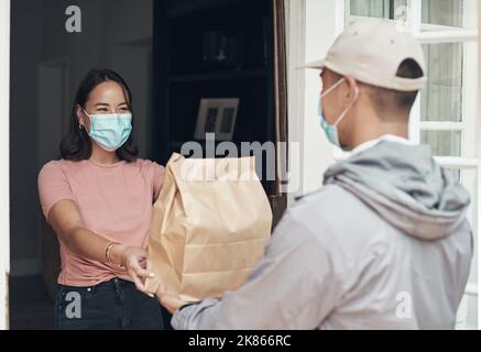 Ihre Bestellung ist meine Lieferung. Ein junger Mann liefert ein Paket an einen Kunden zu Hause. Stockfoto