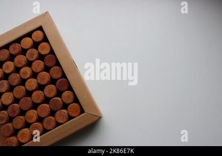 Konzept für Postkarte oder Hintergrund. Pappkarton mit Reihen von Weinkorken auf weißer Oberfläche gedreht auf einer Seite des Bildes Stockfoto
