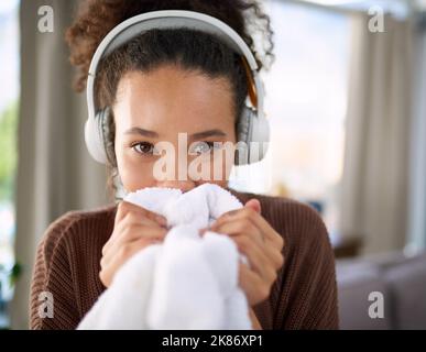 Es sieht sauber aus und es riecht auch. Eine Frau riecht frisch gewaschene Wäsche, während sie zu Hause sitzt. Stockfoto