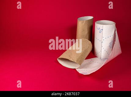 Drei Papierröhrchen aus Toilettenpapier isoliert auf dem roten Hintergrund Stockfoto