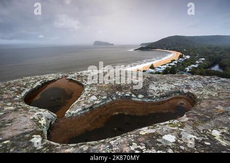 Eine Pfütze in einer felsigen Klippe mit Blick auf Lion Island und Pearl Beach an der Central Coast in Australien Stockfoto