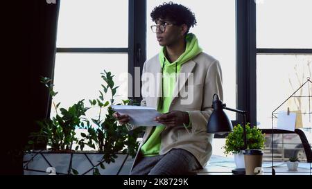Junger afroamerikanischer Designer in Brillen mit Skizzen im Studio Stockfoto