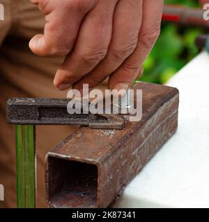 Eine Männerhand schraubt einen Bolzen in eine Metallmutter. Arbeiten mit Metall Stockfoto