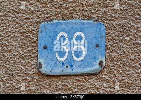 Hausname Nummer 38 in weiß auf blauem Hintergrund, auf einer alten verputzten Wand geschrieben Stockfoto